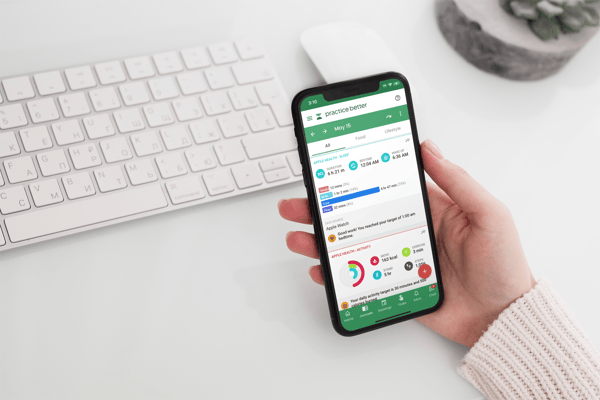 A person's hand holding a mobile phone with the Practice Better app on the screen.