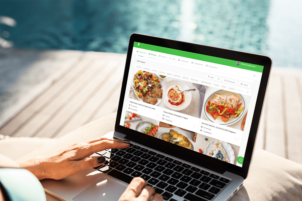 A person sitting poolside views a selection of recipes from That Clean Life on their laptop